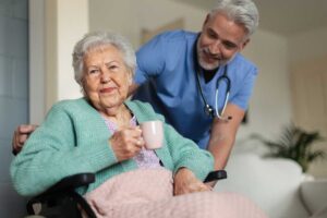 Senior couple sits together in an assisted living apartment while a caregiver reviews an individual care plan.